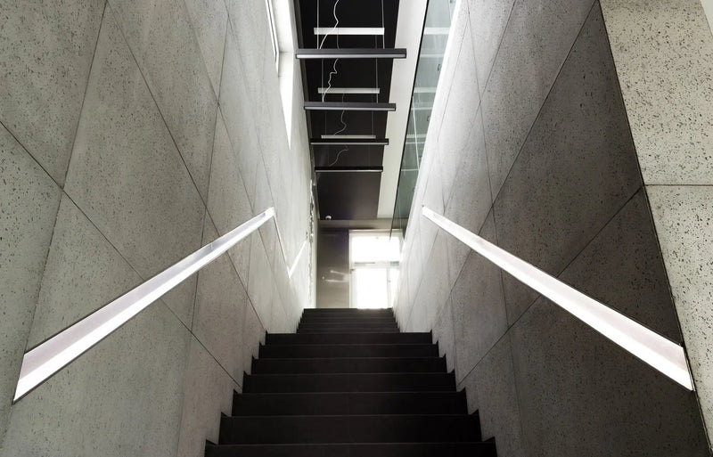 Modern staircase with concrete walls and a light fixture in an indoor setting.